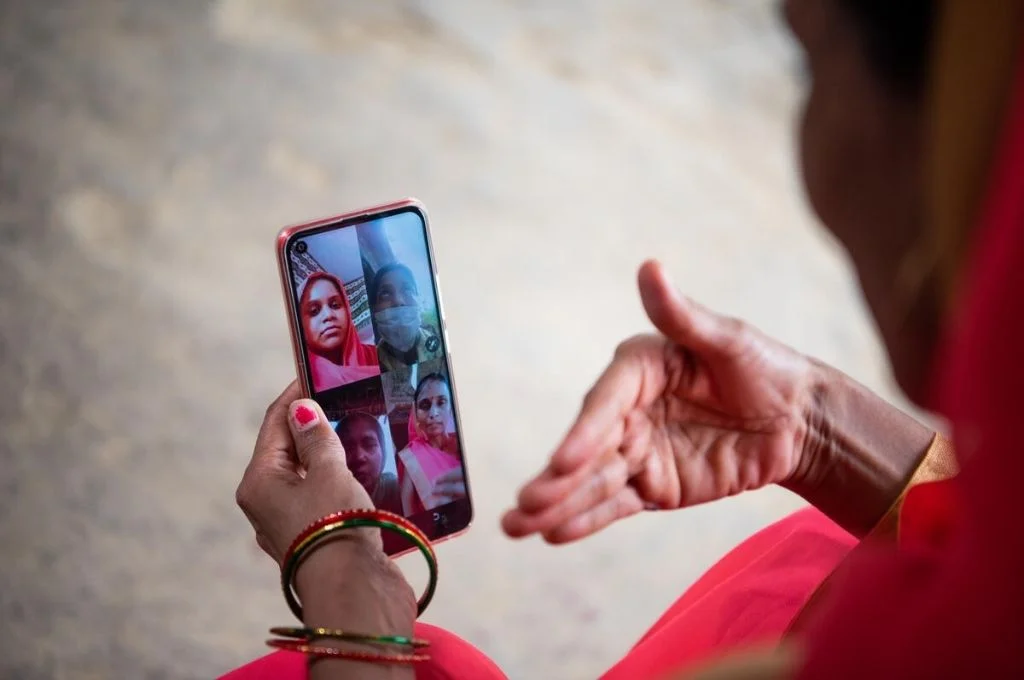 एक आंगनबाड़ी कार्यकर्ता टेलीकाउन्सेलिंग के लिए लाभार्थी महिलाओं के एक समूह को स्मार्टफोन से वीडियोकॉल करते हुए_गेट्स आर्काइव/सौम्या खंडेलवाल-कोविड-19 संचार