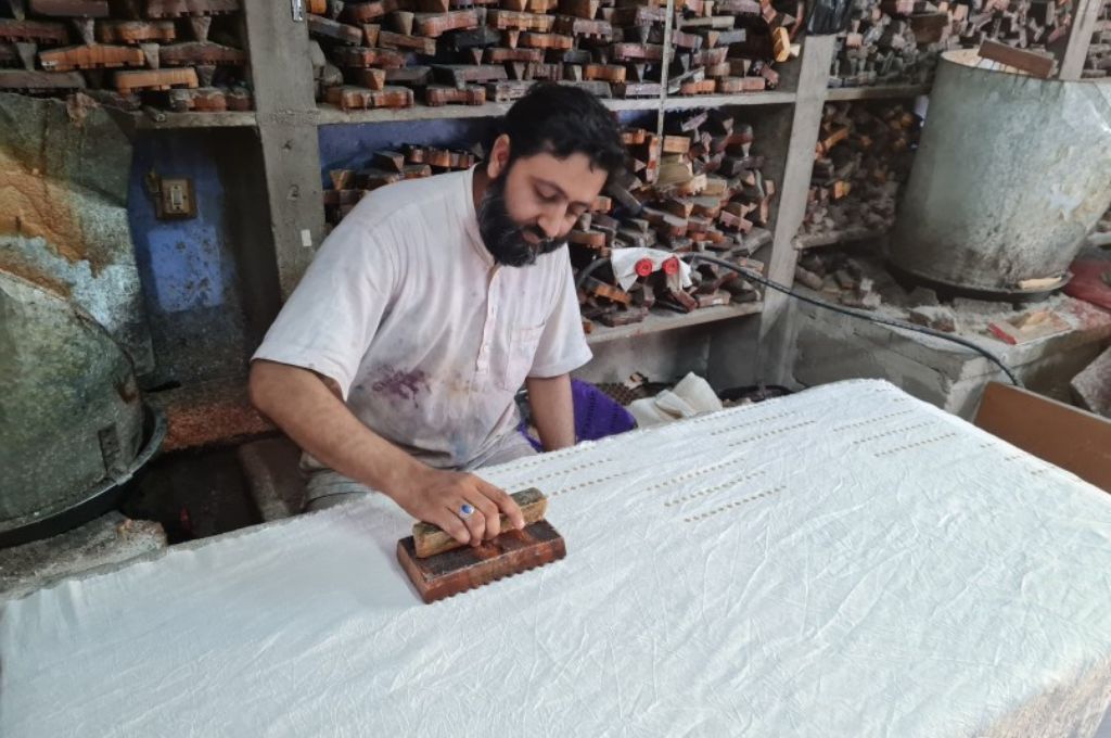 शकील खत्री, एक बाटिक शिलकर कपड़े पर प्रिंट करने के लिए हैंड ब्लॉक का उपयोग करते हैं-बाटिक कच्छ