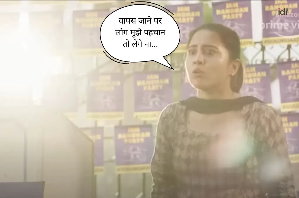 एक महिला धूप में खड़ी है, चिंतित और घबराई हुई नजर आ रही है। पीछे दीवार पर किसी राजनितिक पार्टी के कई पोस्टर लगे हैं। एक डायलाग बॉक्स में लिखा है: "वापस जाने पर लोग मुझे पहचान तो लेंगे ना"_फील्ड ट्रिप 