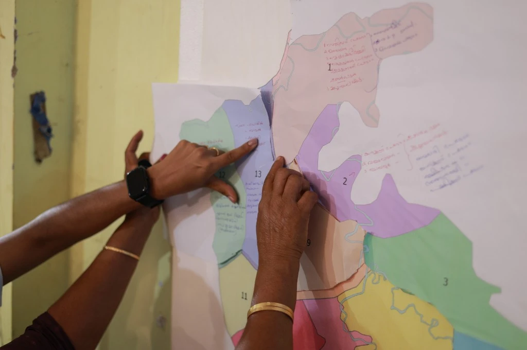 हाथ से नक्शे मिलाते हुए प्रतिभागी बाढ़ प्रभावित हिस्सों को पहचानने का प्रयास कर रहे हैं__आपदा प्रबंधन