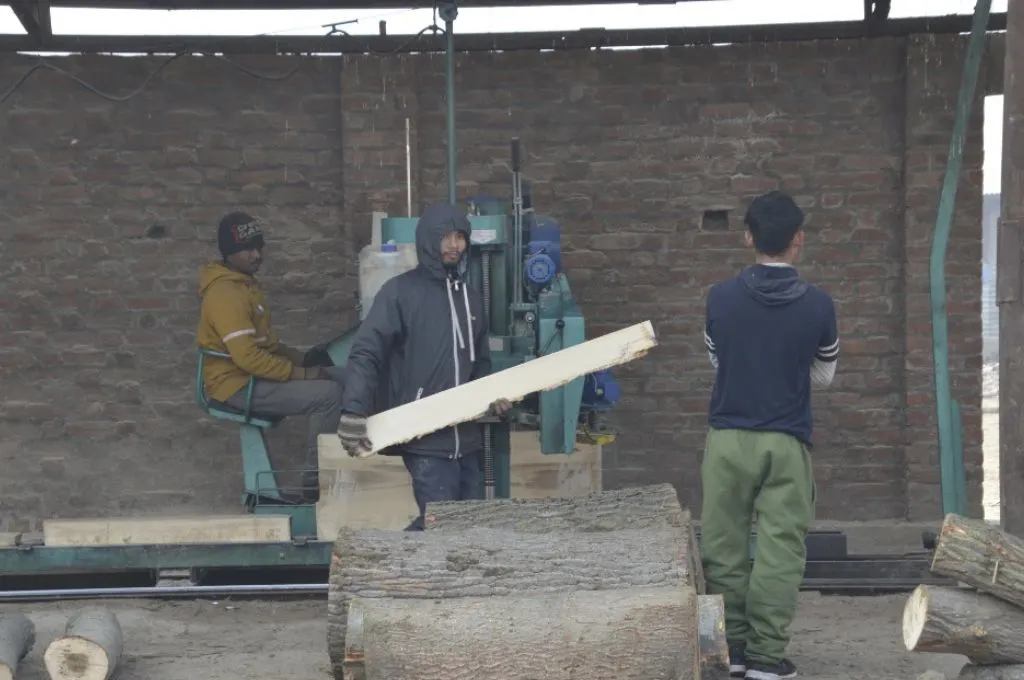 लकड़ियों को पेंसिल साइज़ में मशीन से काटते मजदूर_पेंसिल उद्योग