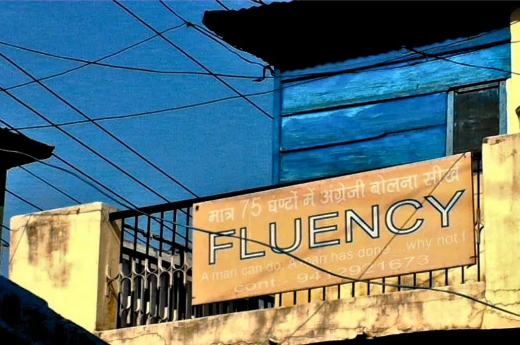 छज्जे पर टंगा हुआ बोर्ड जिसमें फ्लुएंसी लिखा हुआ है— हिंदी दिवस