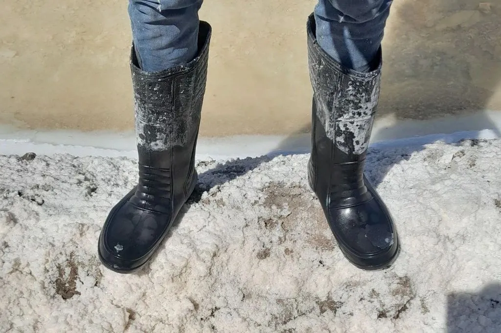नमक की खेती करने वाले एक श्रमिक के पैरों की तस्वीर, जिसमें उन्होंने लंबे बूट पहने हुए हैं_सॉल्ट पैन 