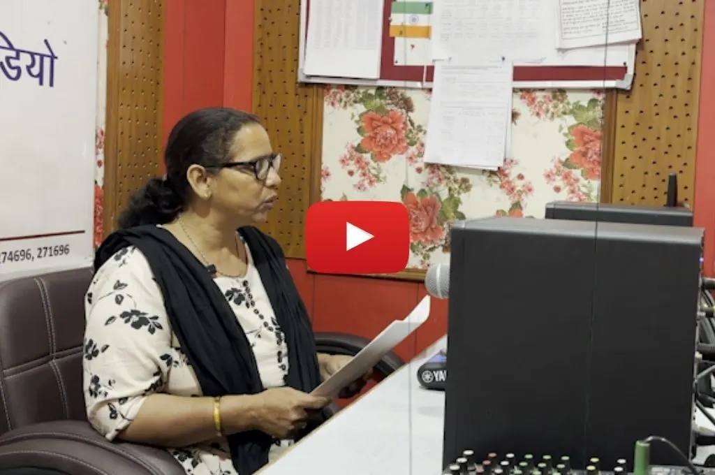 रिकॉर्डिंग स्टूडियो में माइक पर कागज से पढ़कर बोलती एक प्रौढ़ महिला_सामुदायिक रेडियो