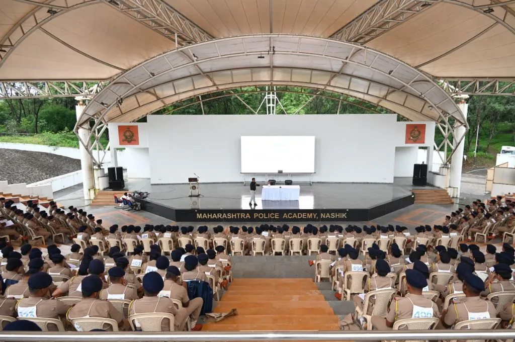 एक सभागार एवं मंच में वर्दीधारी लोग_जमीनी कार्यकर्ता