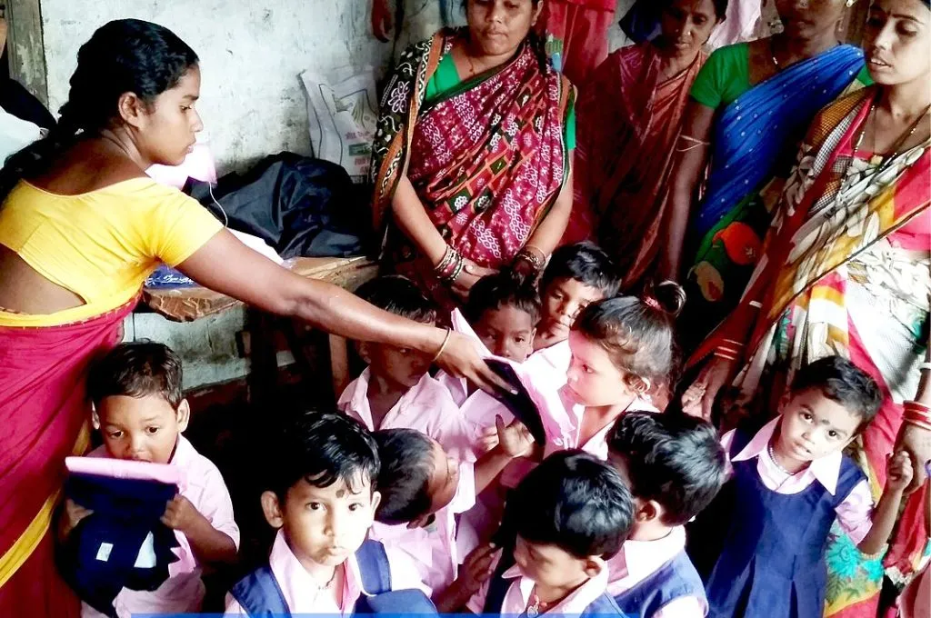 आंगनवाड़ी में कुछ बच्चों को पुस्तक दिखाती एक आंगनवाड़ी कार्यकर्ता_आंगनवाड़ी कार्यकर्ता