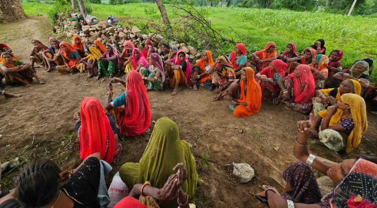 महिलाओं का एक जनसमूह ज़मीन पर बैठकर बातचीत करते हुए_वीबी-जी राम जी